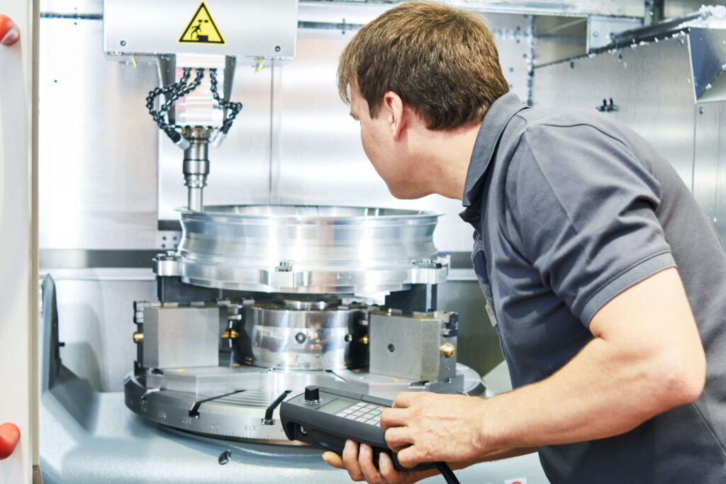 Worker or service engineer operating cnc milling machine at factory